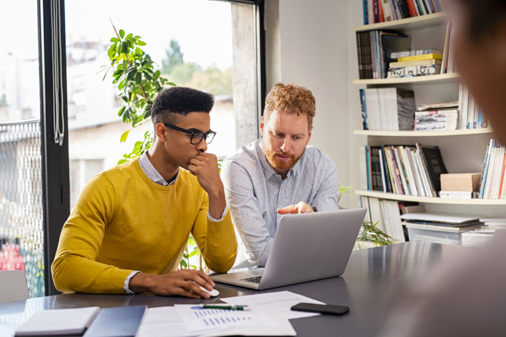 two employees looking at laptop discussing managed it services