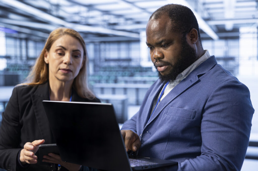 Two professionals consult about cyber insurance while looking at a computer